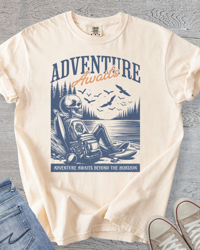 Humorous hiking graphic tee featuring a skeleton relaxing by a lake in Comfort Colors Ivory.
