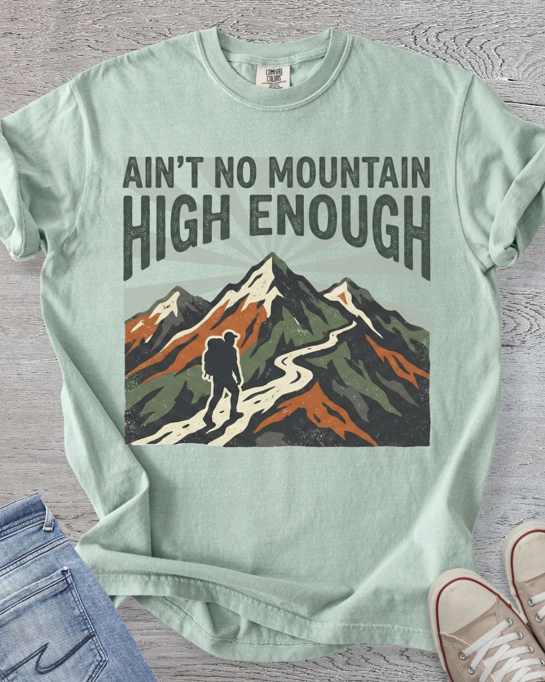 Featuring the iconic lyric “Ain’t No Mountain High Enough,” this premium Comfort Colors t-shirt is shown in Bay.